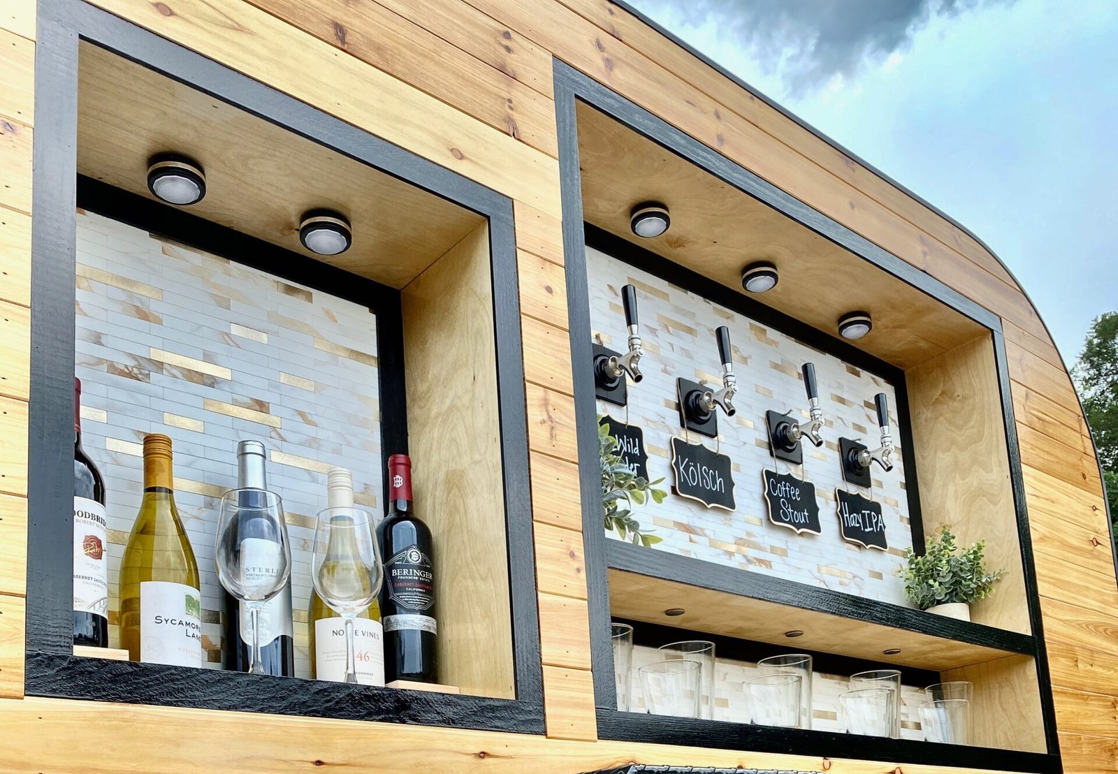 A close up of the tap trailer's wine bottles, glassware and tap wall signage